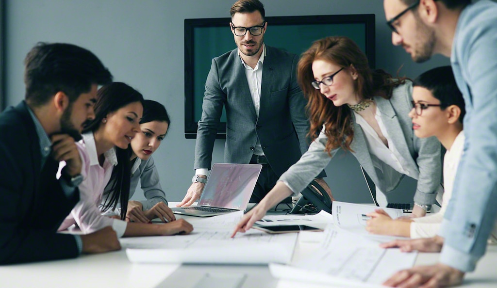 Consulting team collaborating over plans at a conference table